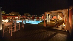 Et poolområde med pool, liggestole og en bar.