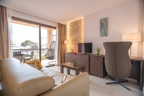 Habitación de hotel moderna con sofá, televisión, escritorio y balcón.