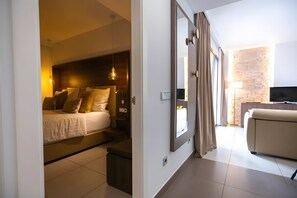 Habitación de hotel moderna con cama, mesita de noche, lámpara, televisor y vistas al exterior.