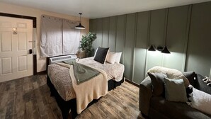 Un dormitorio con cama, mesita de noche, lámpara y una silla.