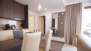 A modern kitchen with dark wood cabinets, a dining table with chairs, a coffee maker, and a hanging light fixture. - Apartment 'Suite 3' with Shared Pool, Wi-Fi and Air Conditioning (Cala Agulla)