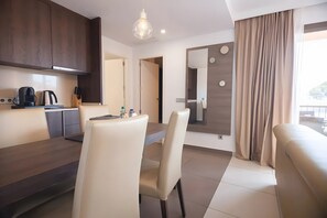 Una cocina moderna con armarios de madera oscura, una mesa de comedor con sillas, una cafetera y una lámpara colgante.