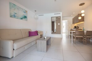 A modern living room with a sofa, coffee table, and a dining area with chairs and a table.