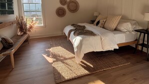 Une chambre à coucher avec un lit, un ventilateur de plafond, une fenêtre et un banc.