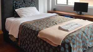 A bedroom with a bed, a desk, a computer, a window with blinds, and a framed picture on the wall. - Bogota San Diego Suite, BogotaUrban Suite, BogotaSuite Planetario, turismobogotá (Bogotá)