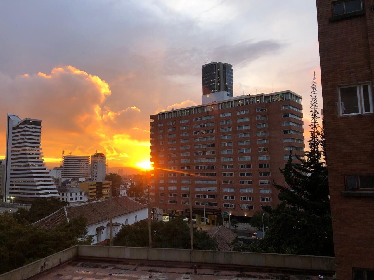A high-rise building with multiple floors, surrounded by other buildings and trees.