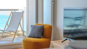 Una sala de estar con un sillón amarillo, un cojín gris y un televisor.