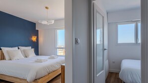 Un dormitorio moderno con una cama de madera, un muro azul decorativo y vistas de la ciudad a través de la ventana.