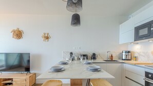 Una cocina moderna con una isla central, taburetes de bar, un televisor de pantalla plana y un microondas.