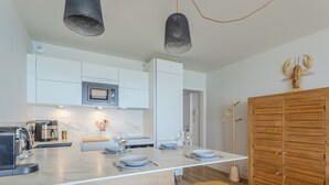Una cocina moderna con armarios blancos, un microondas integrado y una mesa de comedor de madera con taburetes de bar.