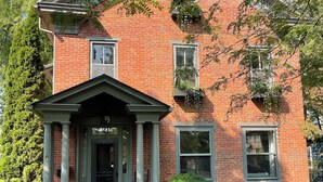 A two-story brick house with a front porch, a central entrance, and a small front yard. - Bright and Sunny Historic 3-bedroom house in quaint Muncy (Muncy)