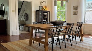 A dining area with a wooden table and chairs, a striped rug, and pendant lighting. - Bright and Sunny Historic 3-bedroom house in quaint Muncy (Muncy)