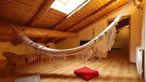 A hammock in a wooden room with a sloped ceiling, a radiator, and a chair. - Apartment 'Alpaga 14' with Private Terrace, Shared Garden and Wi-Fi (Bonneval-sur-Arc)