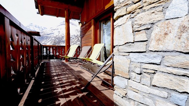 A wooden balcony with stone walls, a wooden railing, and several lounge chairs. - Apartment 'Alpaga 14' with Private Terrace, Shared Garden and Wi-Fi (Bonneval-sur-Arc)