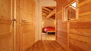 A wooden interior with a bed, a door, and a window. - Apartment 'Alpaga 14' with Private Terrace, Shared Garden and Wi-Fi (Bonneval-sur-Arc)