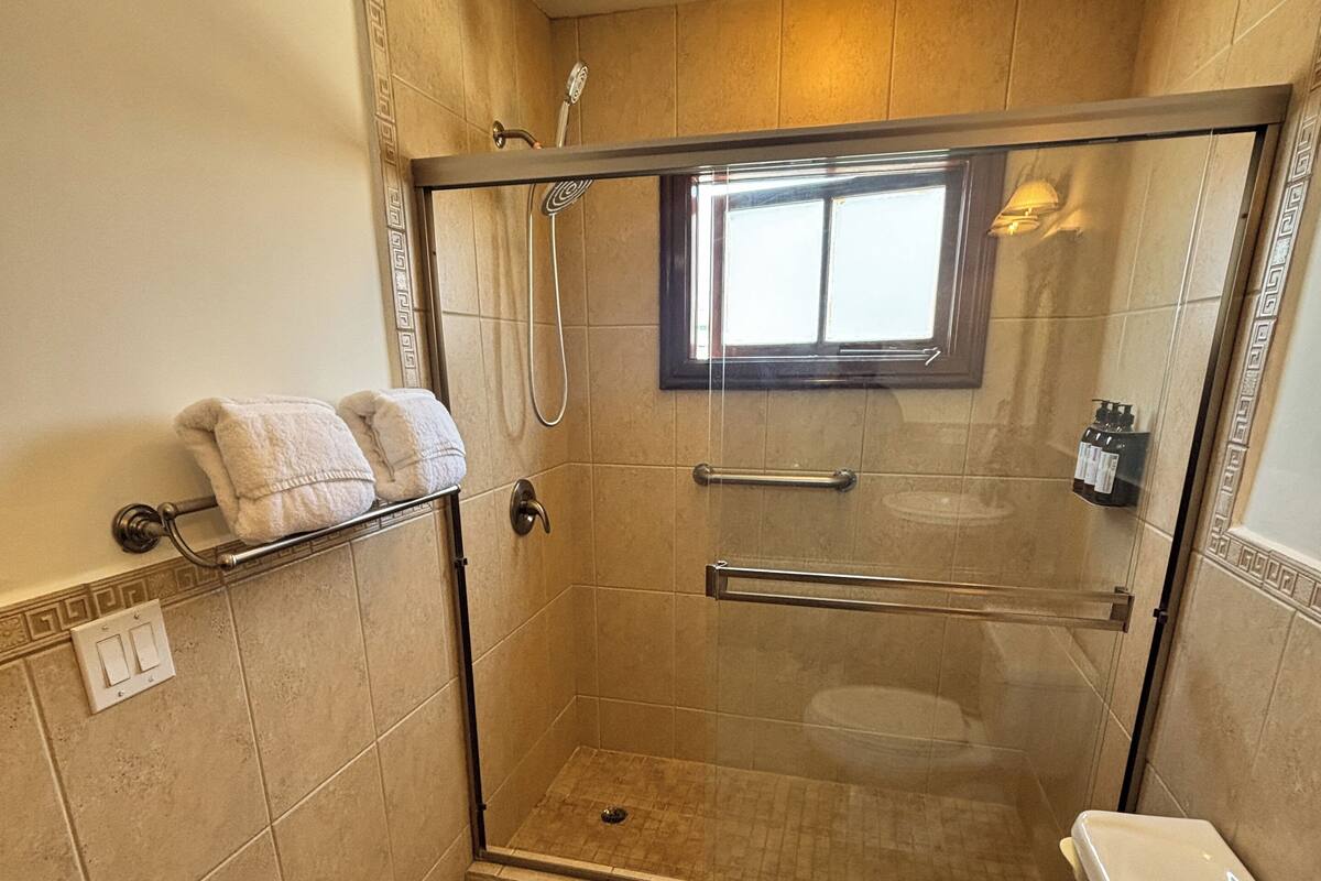 Eine Duschkabine mit Fenster, Toilette und Handtuchhalter mit Handtüchern.
