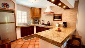 A kitchen with granite countertops, a built-in oven, a microwave, and a coffee maker.