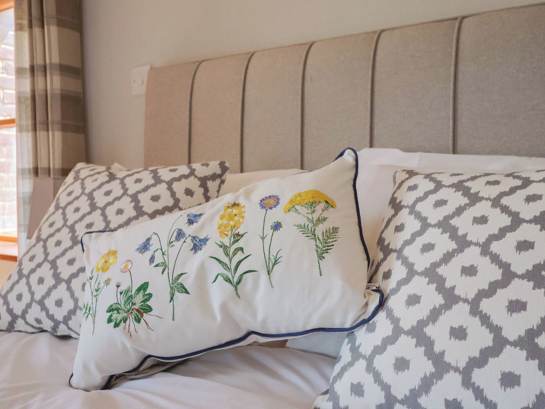 A bed with patterned pillows and a headboard.