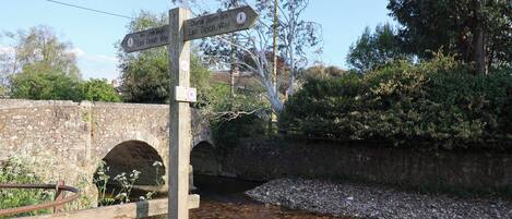 A wooden signpost with directional arrows pointing towards '9m Lyme Regis' and 'Church Green 6m East Devon Way'.