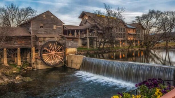 A rustic wooden building with a large water wheel and a waterfall. - King Bed~Hot Tub~Serene setting~Romantic (Sevierville)