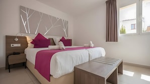 A bedroom with a bed, bedside table, lamp, and a window with curtains.