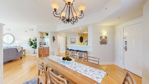 A spacious dining area with a wooden table, chairs, and a chandelier. - Serene 5th floor Villa with Two Balconies! (Hilton Head)