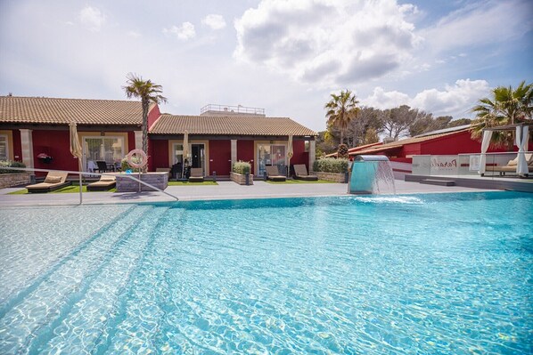 A swimming pool with lounge chairs and a building with a tiled roof.