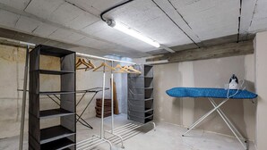 Une pièce équipée d’une étagère métallique, d’un étendoir et d’un luminaire au plafond.