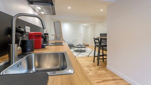 Une cuisine moderne avec un évier en acier inoxydable, une machine à café rouge et une chaise noire.