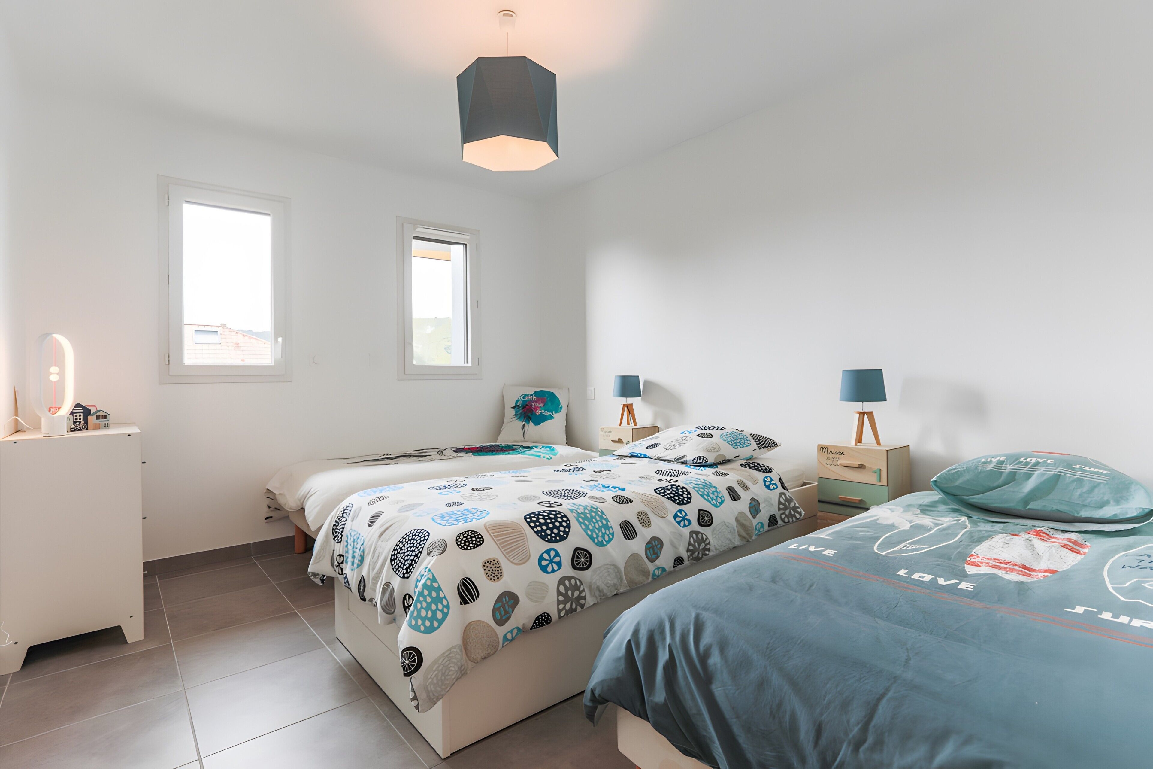 Een slaapkamer met twee bedden, een nachtkastje, een lamp en een raam.