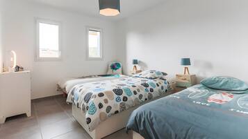 Een slaapkamer met twee bedden, een nachtkastje, een lamp en een raam.