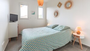 A bedroom with a bed, bedside tables, a TV, and decorative wall art.
