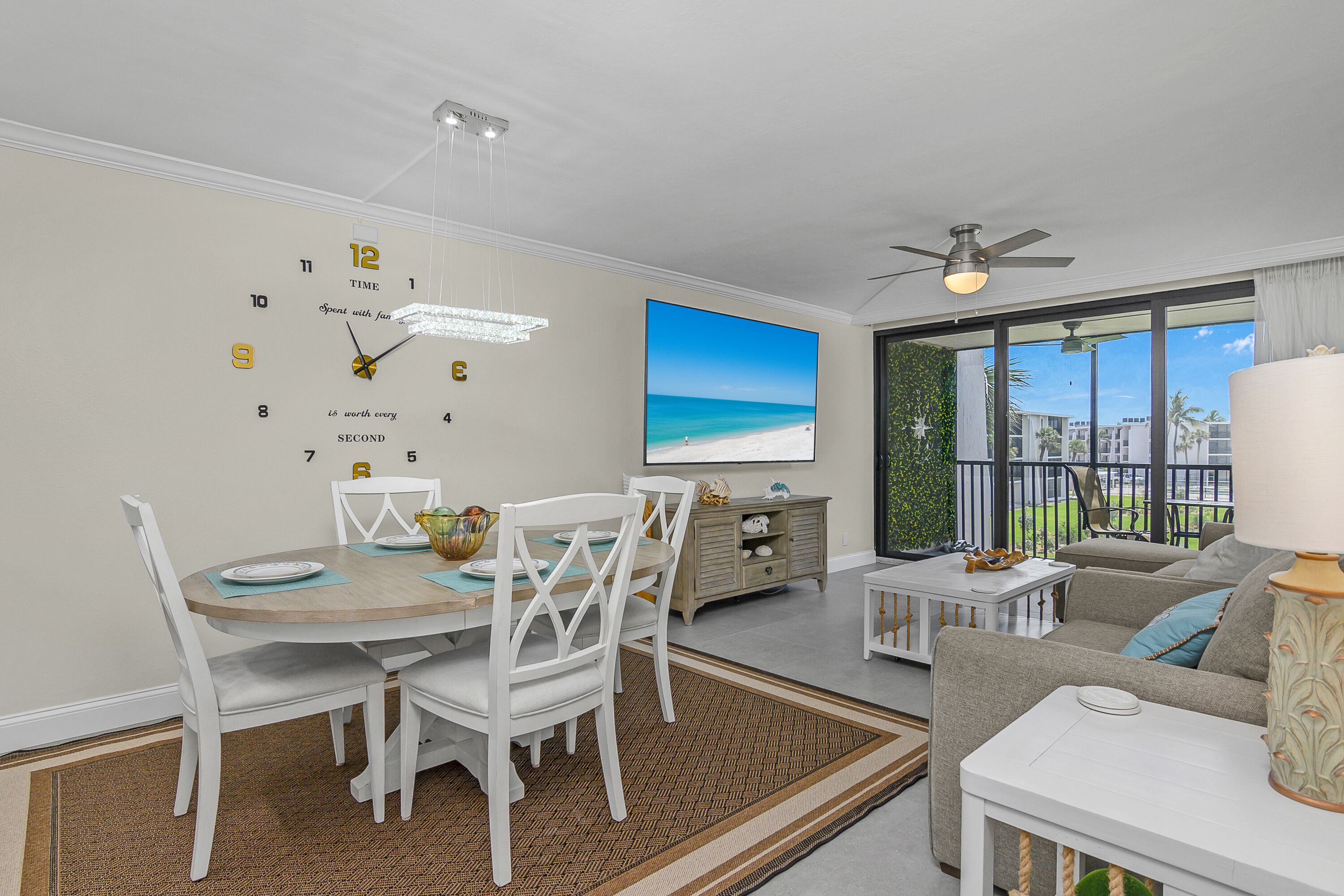 A living room with a dining area, a large TV, and a balcony with a view.