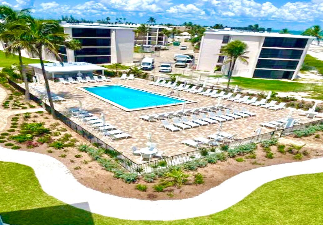 Um hotel com piscina, rodeada por espreguiçadeiras e uma área de estar coberta.