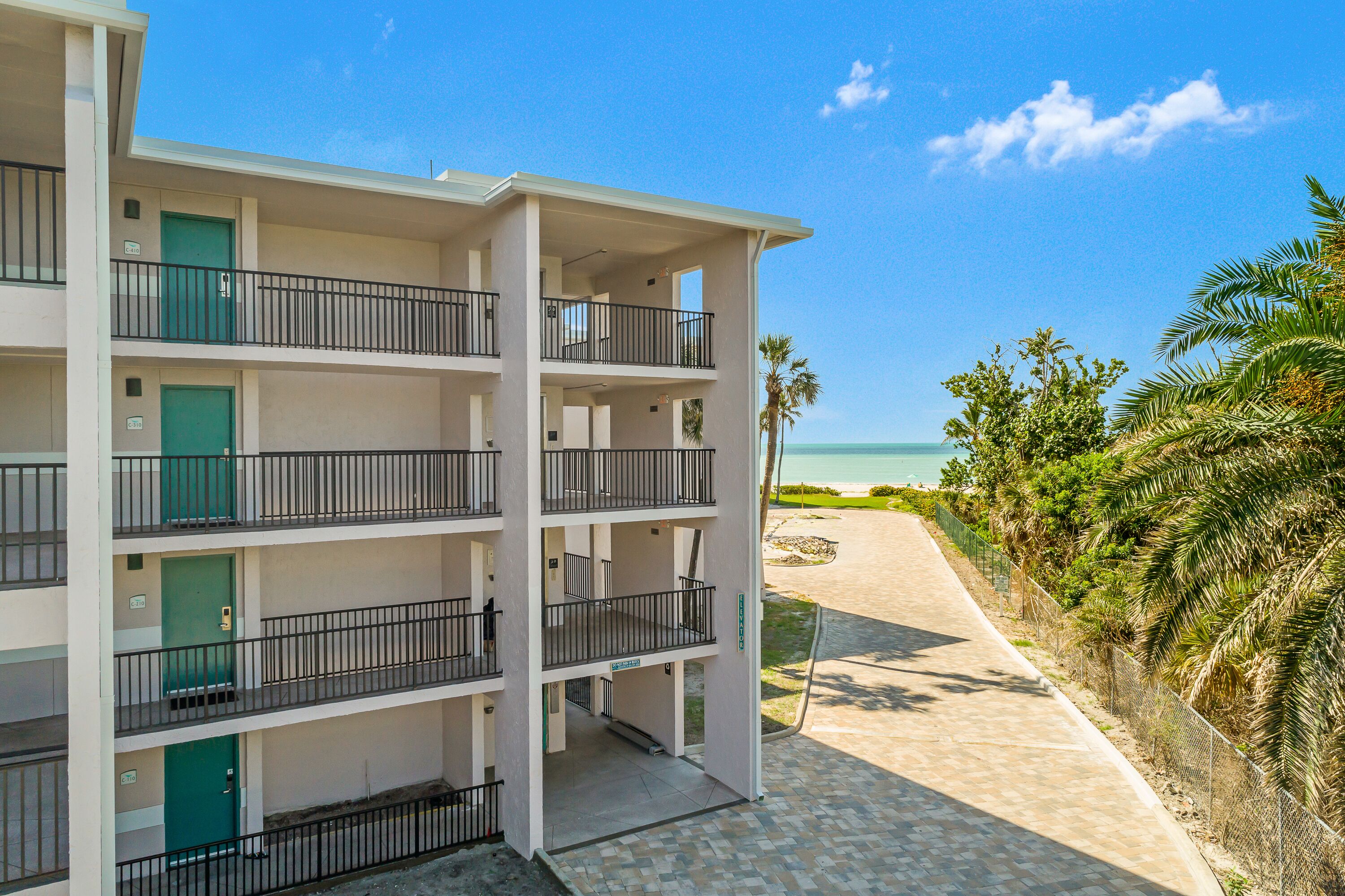 A multi-story hotel with balconies, a beach view, and a paved walkway.