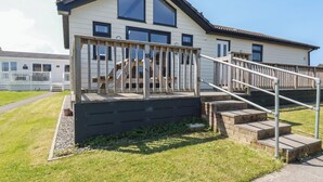 A two-story house with a wooden deck and a staircase leading to the upper floor. - Lodge 18 (Wadebridge)