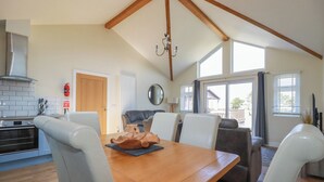 A spacious kitchen with a wooden table and chairs, a built-in oven, and a large window. - Lodge 18 (Wadebridge)