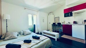 A compact hotel room with a bed, bedside table, a small kitchenette, and a window. - Charming Studio in Montpellier Méditerranée (Montpellier)