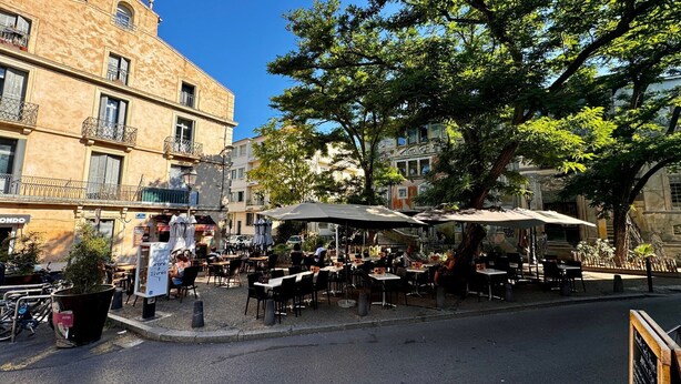 An outdoor café with tables and umbrellas, surrounded by historic buildings and trees. - Charming Studio in Montpellier Méditerranée (Montpellier)