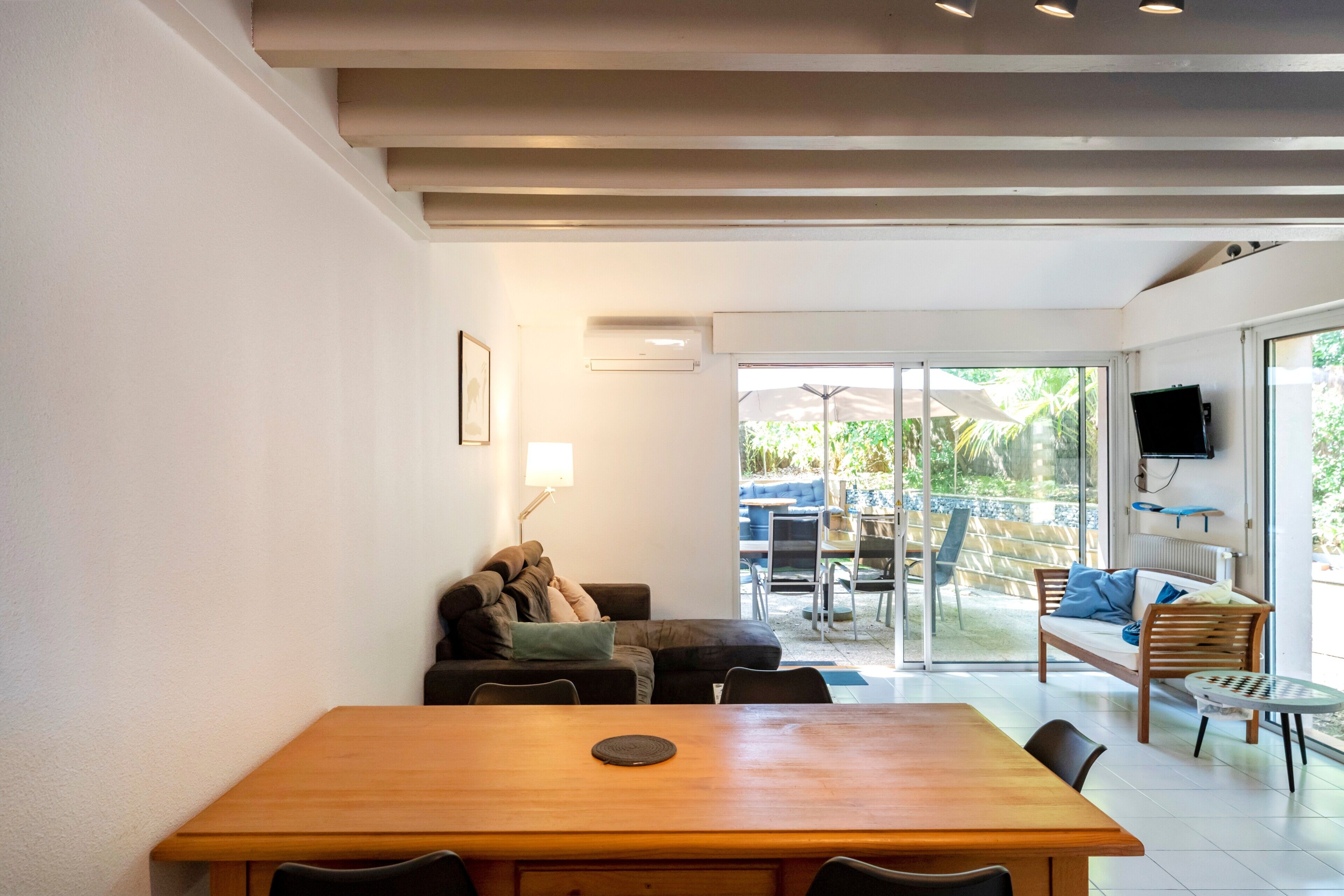 Ein modernes Interieur mit einem Holzespeisetisch, zwei Sofas und einem an der Wand befestigten Fernseher.