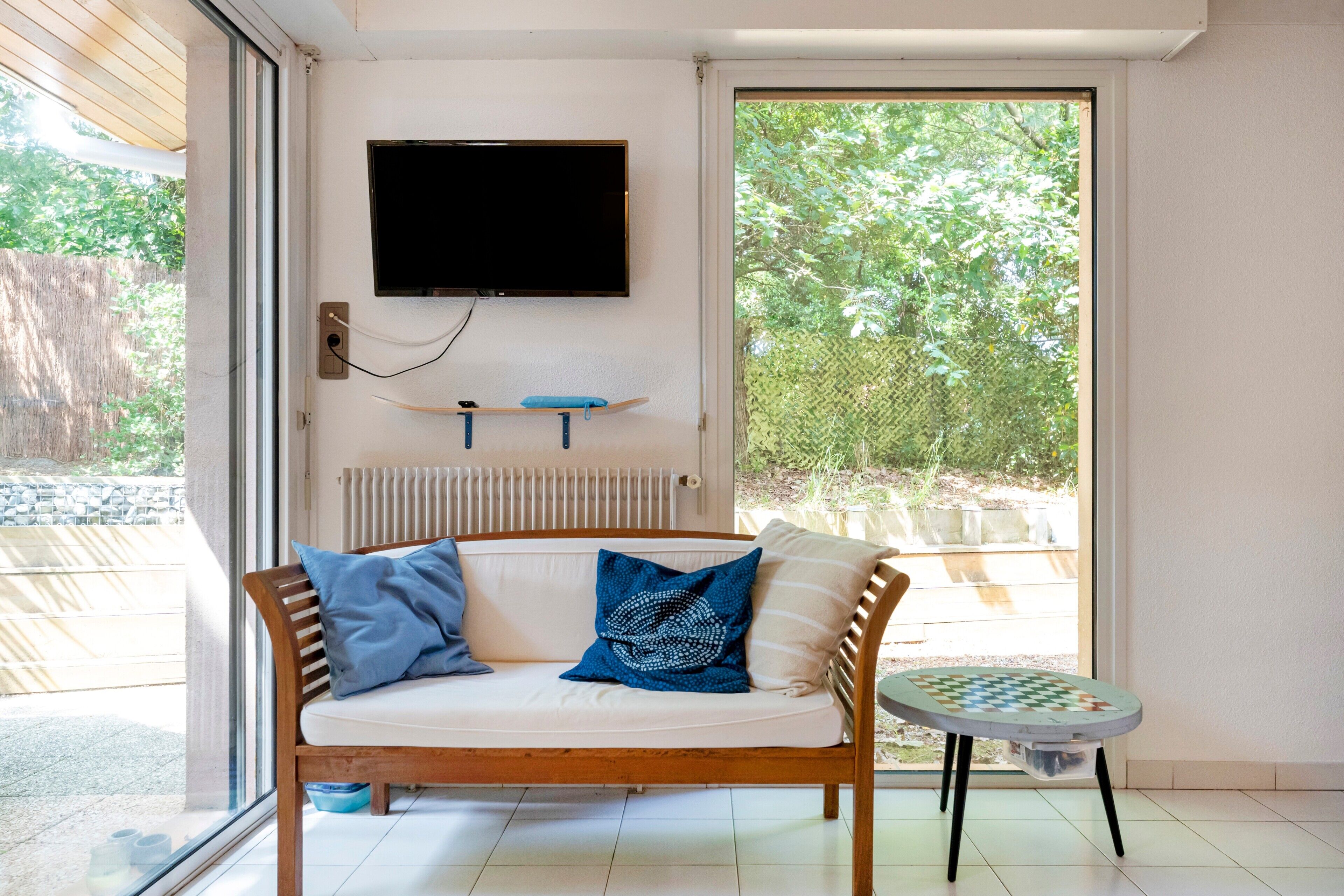 Ein Zimmer mit einer Holzsofa, einem an der Wand befestigten Fernseher und einem kleinen Tisch mit einem Schachbrett.