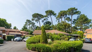 Un quartier résidentiel avec des maisons, des voitures garées et un jardin bien entretenu.
