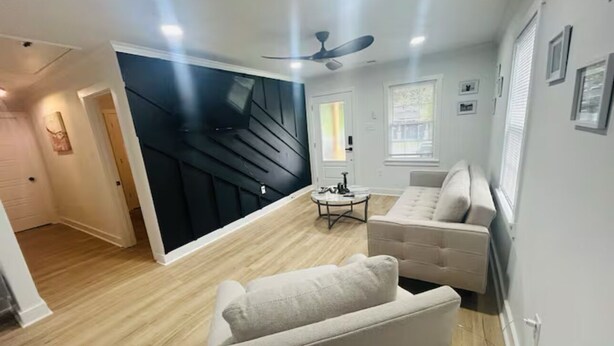 A modern living room with a sectional sofa, a coffee table, and a ceiling fan.