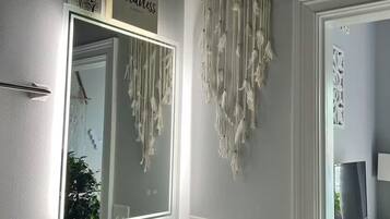 Een badkamer met een grote spiegel, een wastafelmeubel met een wastafel en een dromenvanger aan de muur.