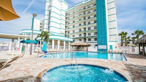 A hotel with a large pool area, multiple balconies, and a tropical theme. - Family Escape | Oceanfront Condo + Pool Access (Cocoa Beach)