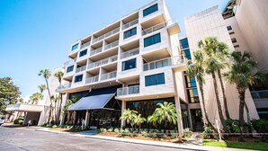 A multi-story hotel with balconies, palm trees, and a covered entrance.