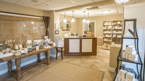 Le hall d’un hôtel-boutique comprenant un comptoir d’accueil, un présentoir de produits de toilette et une bibliothèque.