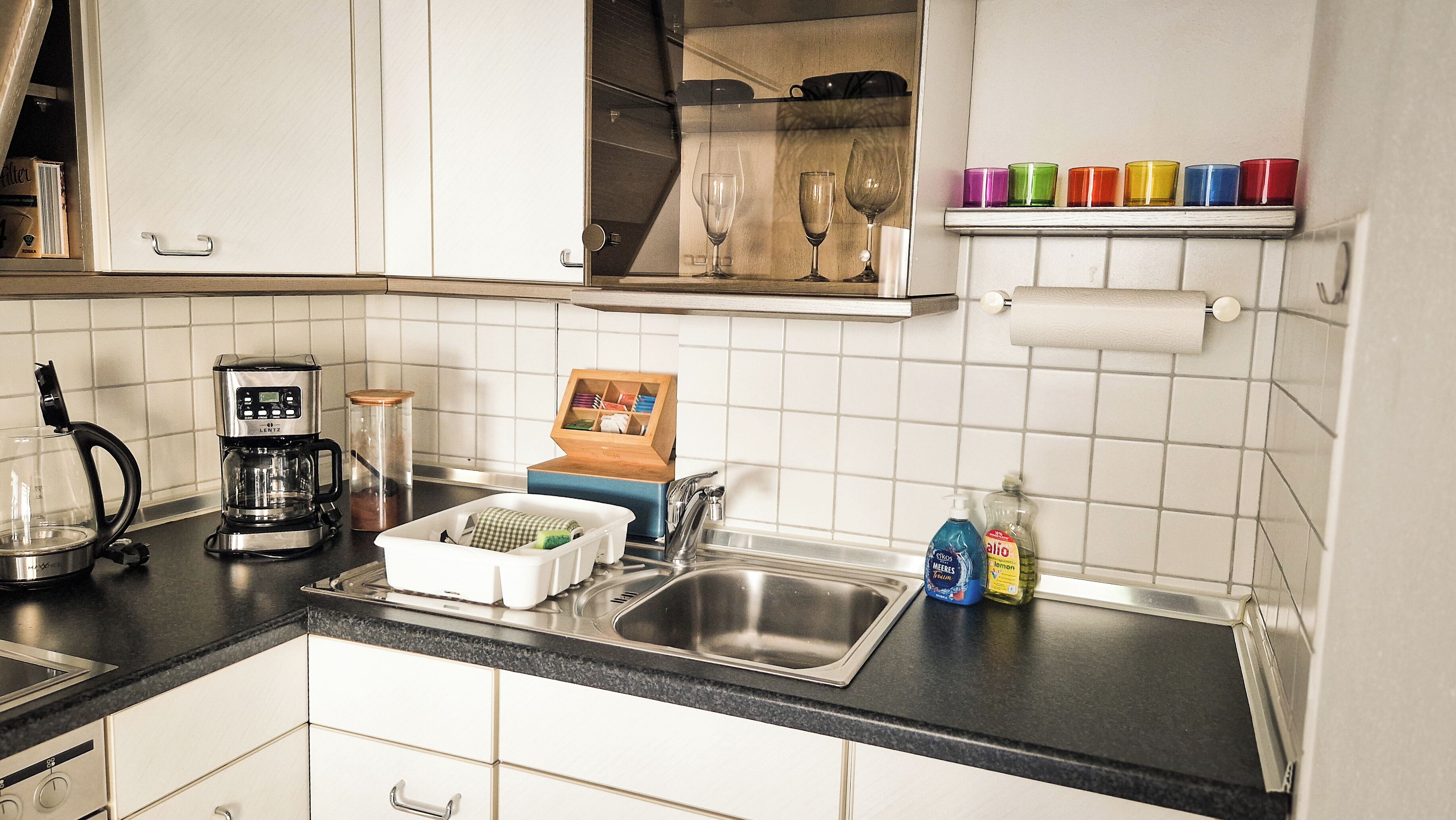 A kitchen with a coffee maker, a sink, and a dish rack.