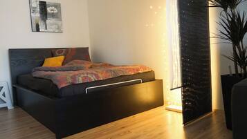Ein modernes Schlafzimmer mit Bett, Nachttisch und einem großen Fenster mit Vorhängen.