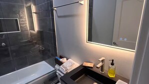 A modern bathroom with a bathtub, toilet, and sink.